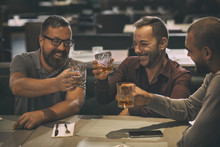 Cheerful Smiling Men Holding Glasses With Alcohol Beverages And Laughing. Three Friends Spending Time Together And Having Fun In Bar. Men Drinking Scotch, Whiskey Or Brandy.