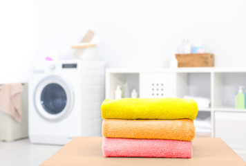 Canvas Print - Colorful clean towels on table in laundry room, space for text