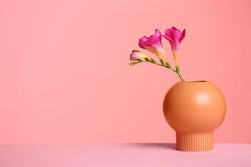 Wall Mural - Stylish vase with beautiful flower on table against color background, space for text
