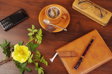  Cup of coffee, flower, notebook and pen on a wooden table