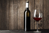 Fototapeta Panele - Glass and bottle with delicious red wine on table against wooden background