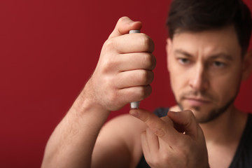 Poster - Diabetic man taking blood sample with lancet pen on color background