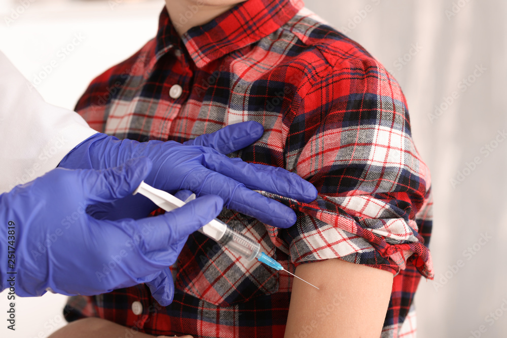 Doctor vaccinating child against flu in clinic