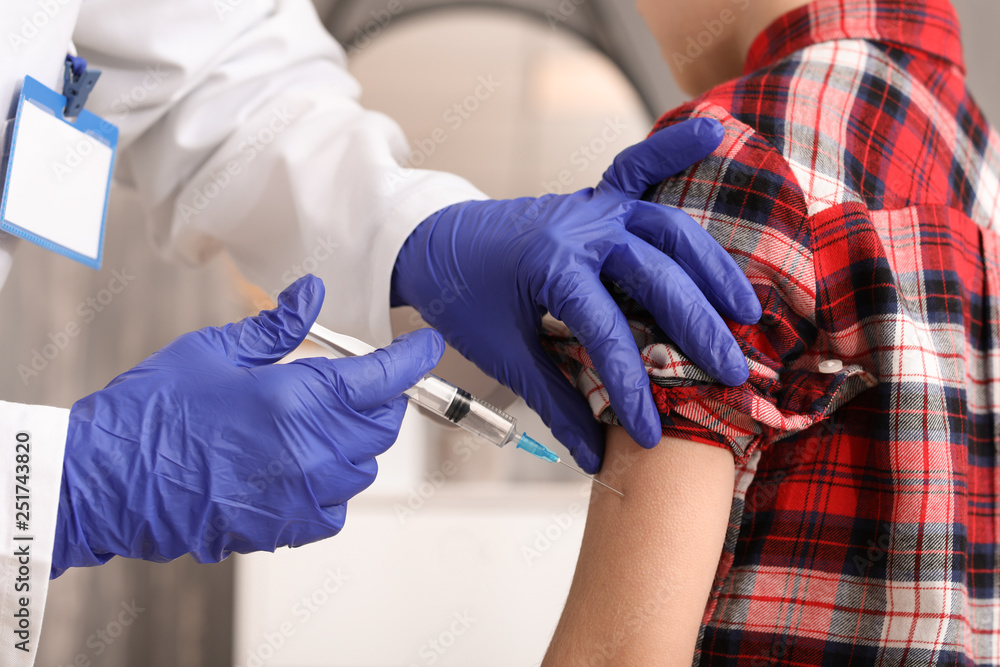 Doctor vaccinating child against flu in clinic