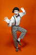 © rh2010 - Full length portrait of an actor as a pantomime with white facial makeup showing expressive emotions on the orange background