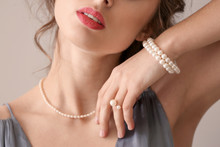 Young Woman With Beautiful Pearl Jewelry On Light Background, Closeup