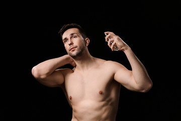 Wall Mural - Handsome man with bottle of perfume on dark background