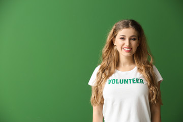 Wall Mural - Young female volunteer on color background