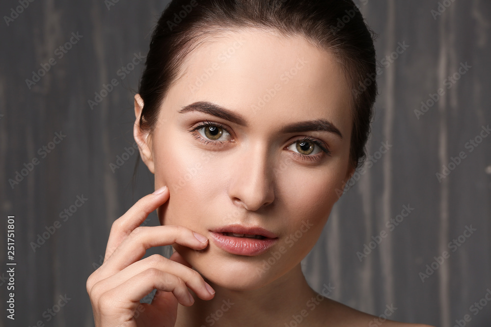 Young woman with beautiful eyebrows on grey background