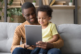 Fototapeta Tulipany - Happy african dad and little son using tablet at home