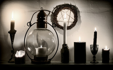 Burning magic candles on the shelf and pentagram on the wall. Magic gothic ritual. Wicca, esoteric, divination and occult background with vintage objects