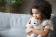 © fizkes - Upset lonely african kid girl holding teddy bear looking away