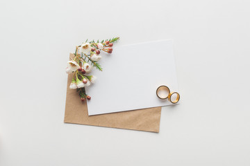 Canvas Print - top view of empty card with brown craft paper envelope and wedding rings on grey background