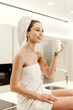 © Anastasia - Beautiful young woman wrapped in towels waking in the morning drinking from a cup in modern kitchen. lifestyle concept