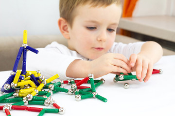 Cute little child boy playing magnets toy for brain development, fine motor skills and creativity concept