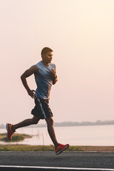 Wall Mural - young man runner running on running road in city park