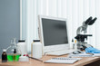 © Dmitriy - Laboratory table with microscope, flasks and a desktop computer above on a window light background. Medicine, pharmacology, pharmacy abstract background.