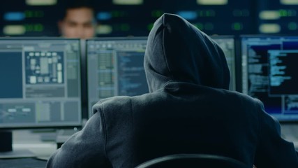 Hooded IT Hacker or Specialist Works on a Personal Computer With Display Showing Software Program with Coding Language Interface