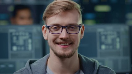 Wall Mural - portrait of a smart and handsome it specialist wearing glasses charmingly smiles at the camera. in t