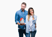 Young Couple In Love Holding House Over Isolated Background Serious Face Thinking About Question, Very Confused Idea