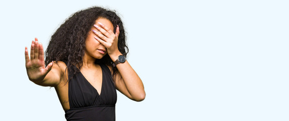 Poster - Young beautiful girl with curly hair wearing fashion skirt covering eyes with hands and doing stop gesture with sad and fear expression. Embarrassed and negative concept.