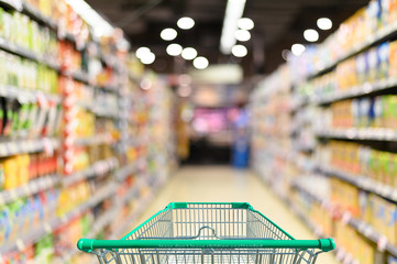 Supermarket aisle with empty green shopping cart