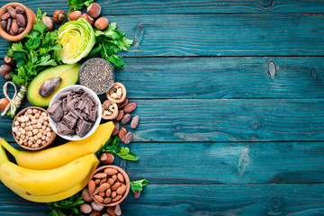 Wall Mural - Foods containing natural magnesium. Mg: Chocolate, banana, cocoa, nuts, avocados, broccoli, almonds. Top view. On a blue wooden background.