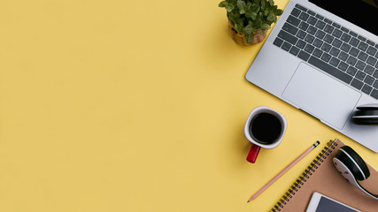 office workspace yellow desk table with laptop, coffee, mobile, notebook, plant. flat lay