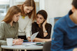 © Nestor - Young girls studying together on same language courses and making project. Beautiful pupils doing their homework exercises after classes. Students preparing interesting presentation together.