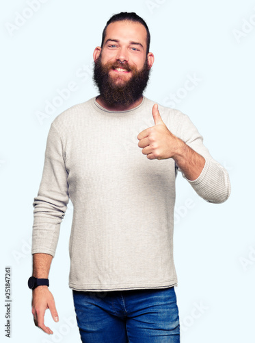 Fotomural Young blond man wearing casual sweater doing happy thumbs up gesture with hand