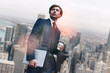 © Friends Stock - New working day. Handsome young businessman holding laptop and cup of coffee while standing against of morning cityscape background