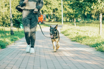 Wall Mural - woman jogging in the park with a German shepherd