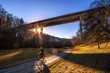 Radfahrer auf Feldweg bei Sonnenuntergang unter einer Brücke