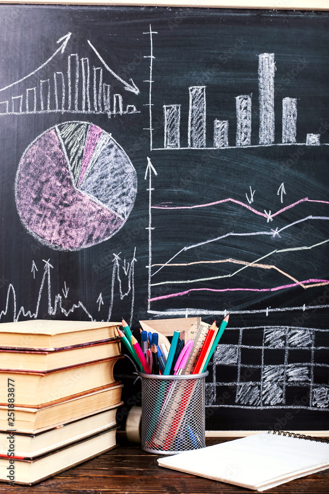 Books on the table against the background of a chalkboard on which are ...