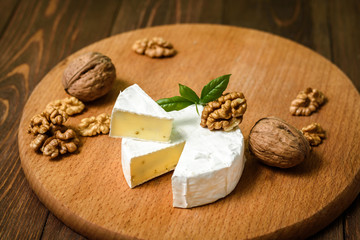 Wall Mural - Camembert or Brie cheese with walnut kernels on wooden wooden background. Copy space. white mold grows on top Penicillium camemberti. 