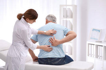 Canvas Print - Chiropractor examining patient with back pain in clinic