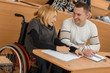 © Zoriana - Happy adult students in wheelchairs sitting together at table, talking and laughing. Smiling man and woman studying at university and getting high education. Concept of spiritual power.