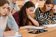 © Zoriana - Side view of serious female student sitting at table during lecture, reading material and preparing for presentation in college. Concentrated pretty girl learning material before test.