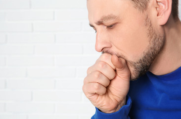 Wall Mural - Man suffering from cough near brick wall. Space for text