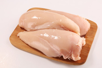 Raw chicken breasts and spices on wooden cutting board, close up