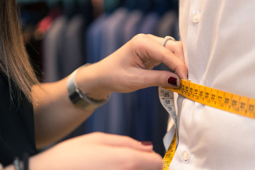 Detail of tailor's hands taking measurements for a man dress