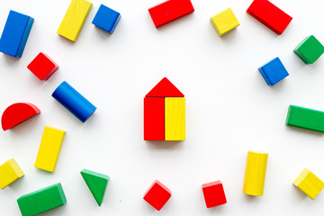 Construction game for kids. Wooden building blocks, toy bricks on white background top view