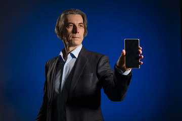 Stylish Businessman shows a mobile phone screen to the viewer.