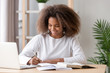 © fizkes - Positive african schoolgirl sitting at desk and study