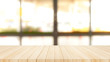 © PRASERT - Wood table top on  with blur glass window wall background.