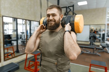 Wall Mural - Muscular caucasian bearded man doing exercises dressed in weighted vest in the gym, military style