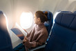 © tonefotografia - Beautiful Asian woman is reading magazine in airplane