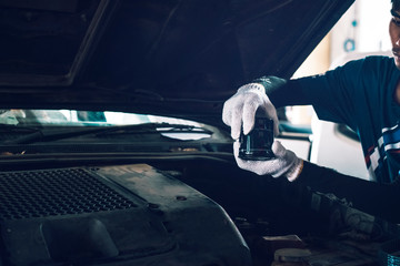 Close up hands of unrecognizable mechanic doing car service and maintenance. Oil and fuel filter changing.