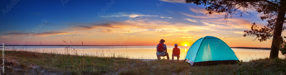 Family resting with tent in nature at sunset - obrazy, fototapety, plakaty 