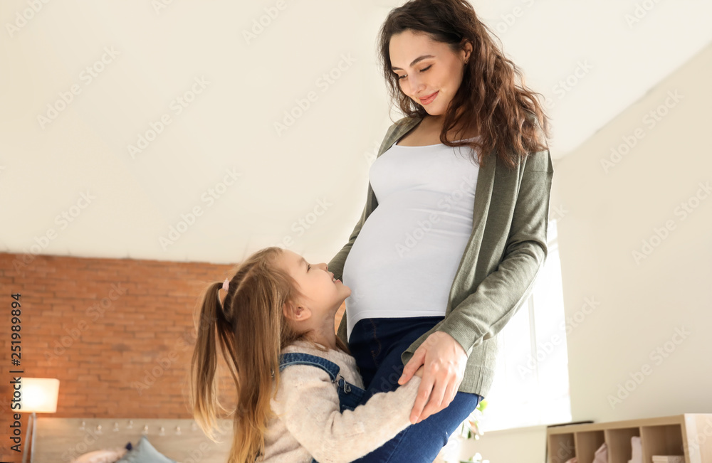 Pregnant mother with little daughter at home